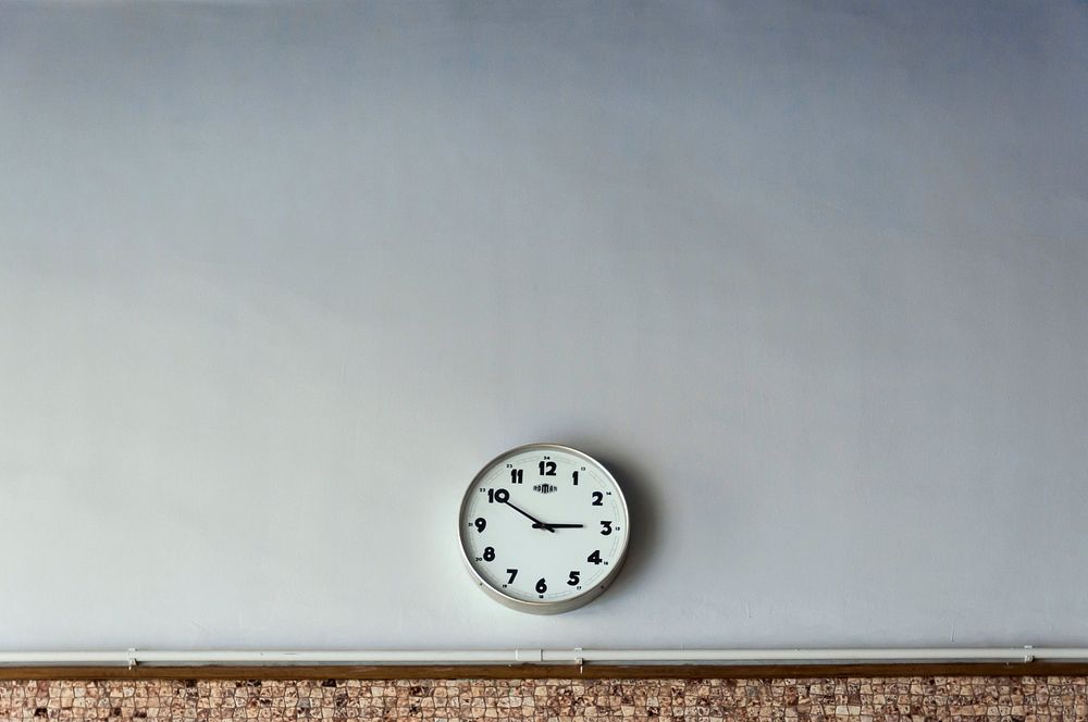 A round analog clock on a white wall. Original public domain image from Wikimedia Commons