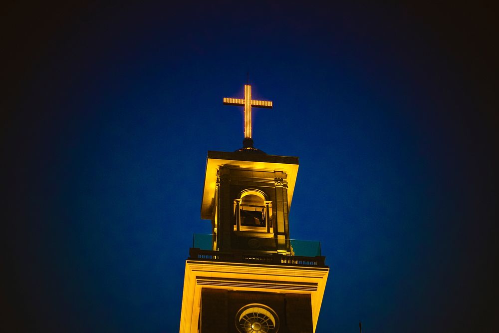 A lighted church steeple and cross against the dark blue night sky in Beirut.. Original public domain image from Wikimedia…
