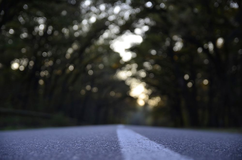 A low shot of the surface of an asphalt road with bokeh effect in the background. Original public domain image from…