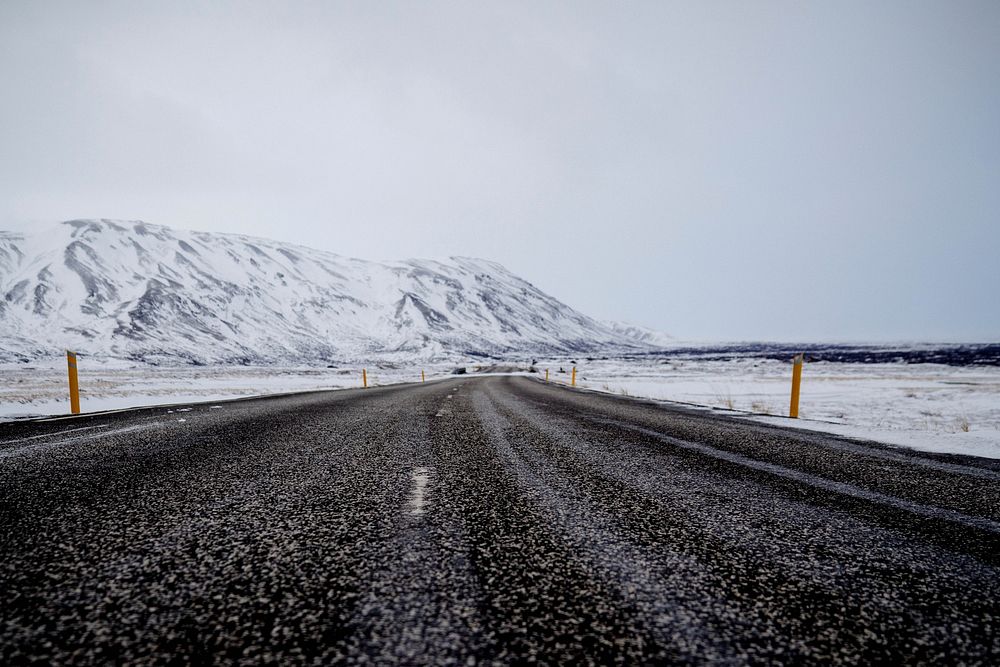 A dark road veers towards a snowy mountain in Iceland. Original public domain image from Wikimedia Commons