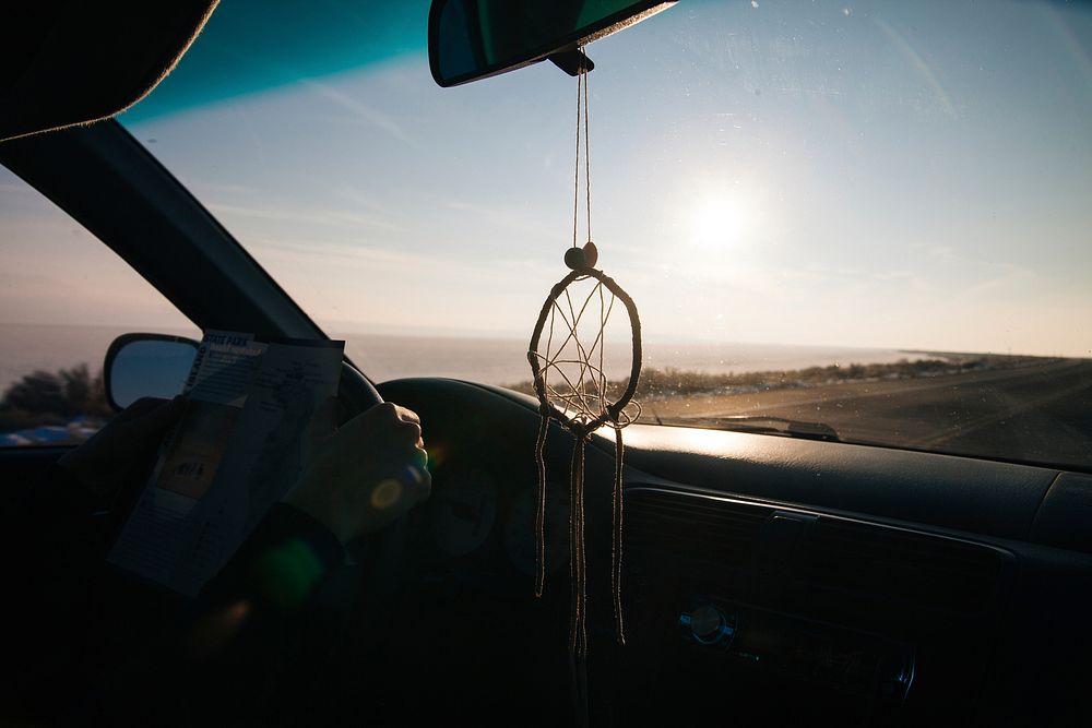 Interior shot from car with dreamcatcher driving on coastal road on Antelope Island. Original public domain image from…