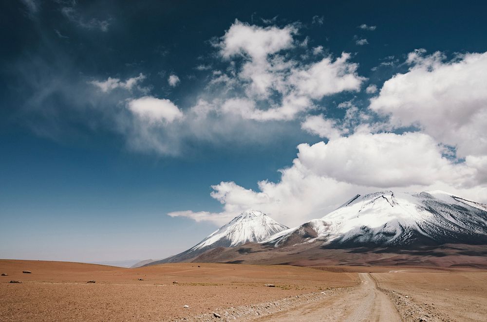 Road in the plains leading to cloud-covered snowy mountains in Licancabur. Original public domain image from Wikimedia…
