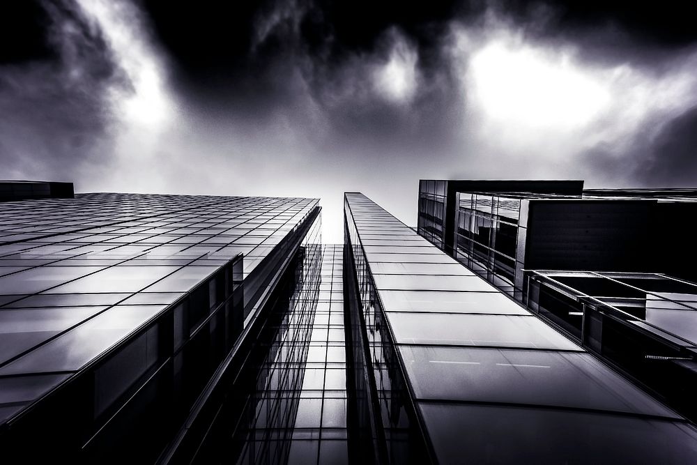 A low-angle shot of a dark glass facade of an office building on a cloudy day. Original public domain image from Wikimedia…