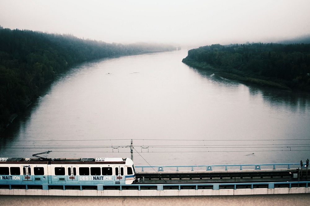 Public transport train on a bridge crosses the river on a misty and cloudy day. Original public domain image from Wikimedia…