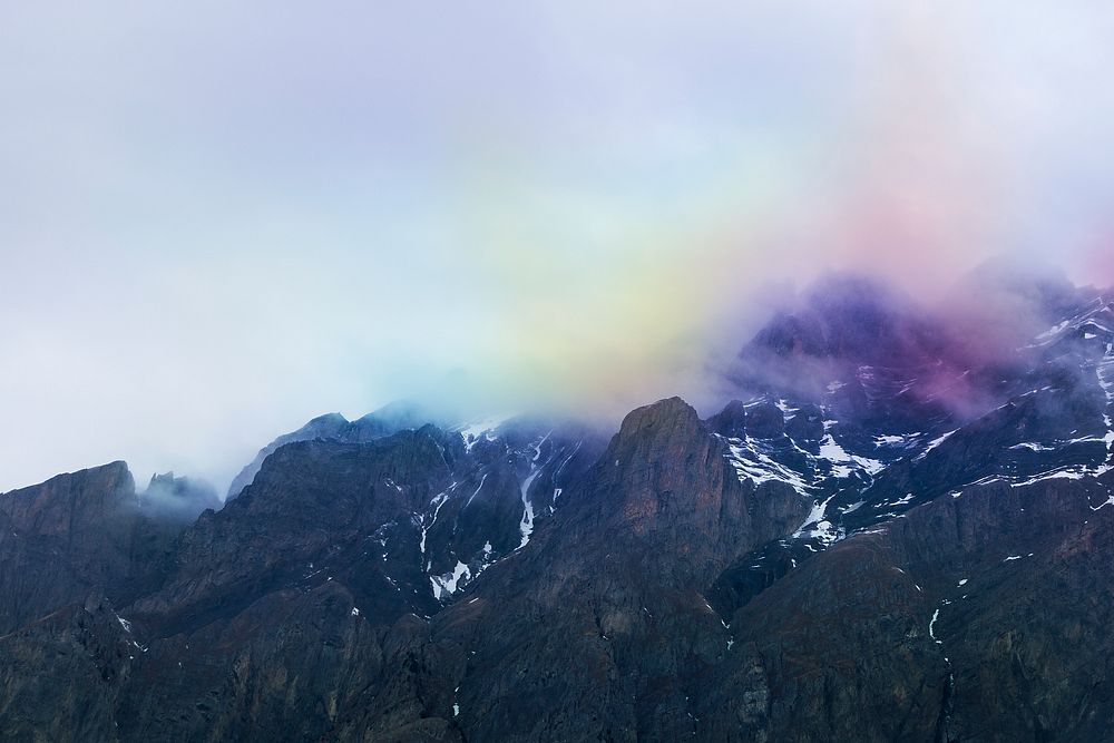 Rainbow colored smoke and clouds over dark mountains in Ovronnaz. Original public domain image from Wikimedia Commons
