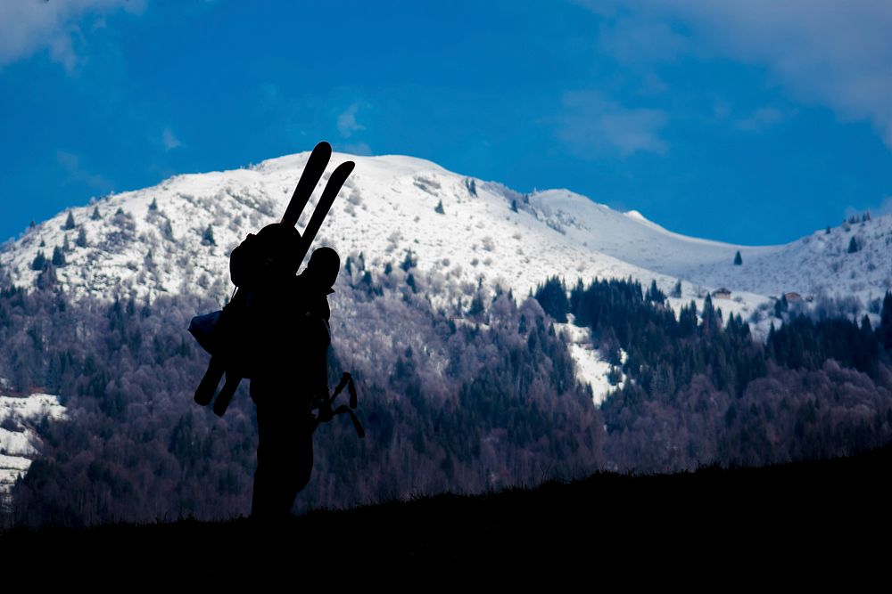 Silhouette of a skier ascending a snowy blue mountain landscape. Original public domain image from Wikimedia Commons