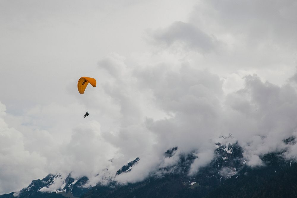 Person with a yellow parachute paragliding in the clouds. Original public domain image from Wikimedia Commons
