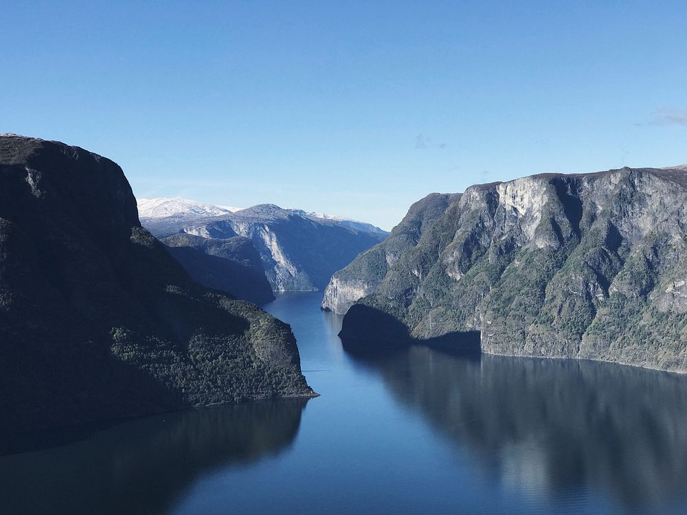 Still water between tall fiords under a blue sky in Aurland. Original public domain image from Wikimedia Commons