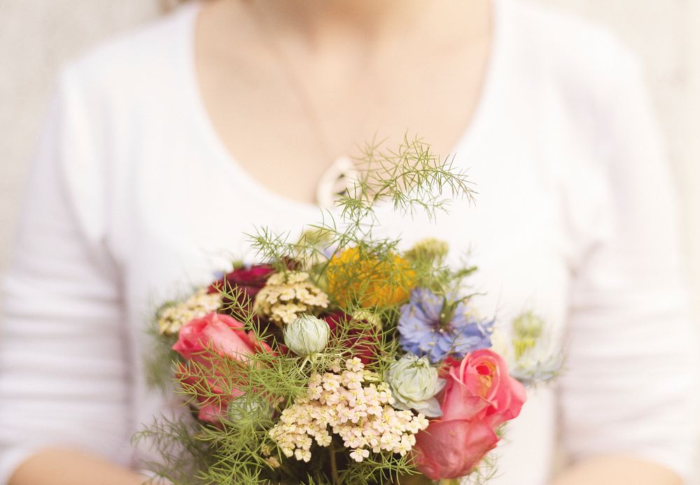 A woman holding a modest bouquet with various flowers. Original public domain image from Wikimedia Commons