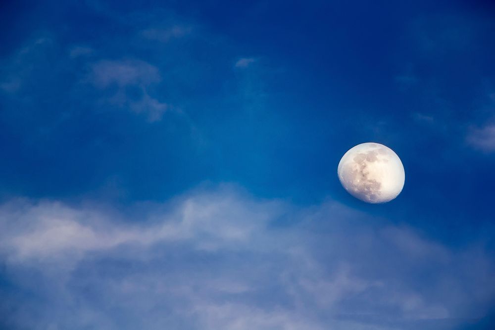 The moon on cloudy blue sky photography. Original public domain image from Wikimedia Commons