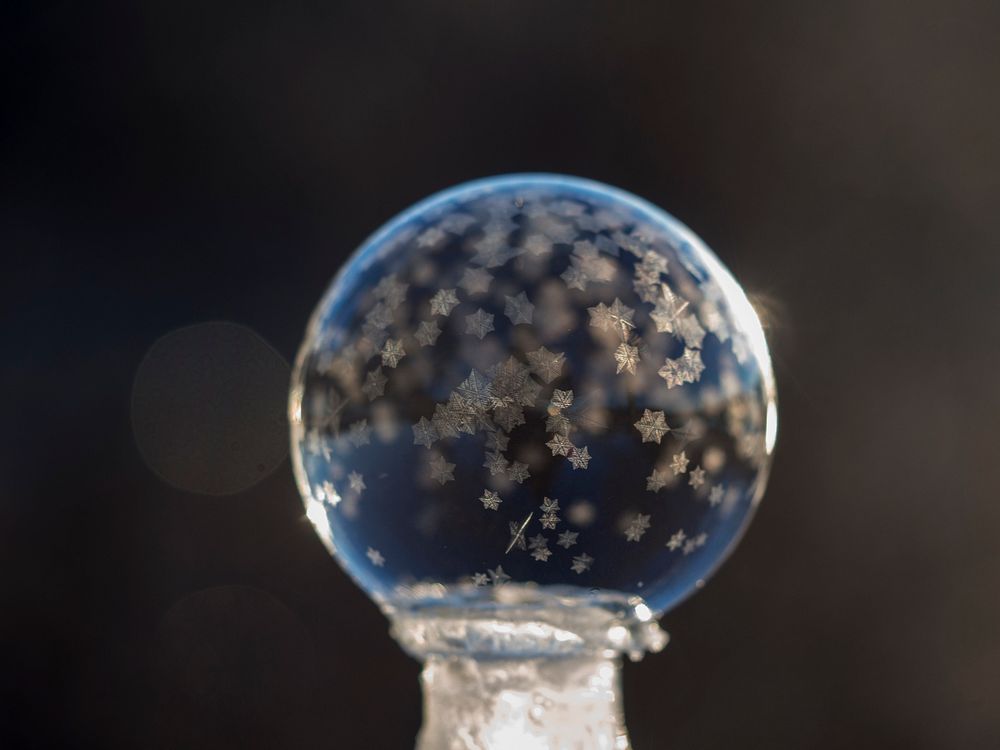 Macro of a frozen bubble with small snowflakes with a black background. Original public domain image from Wikimedia Commons