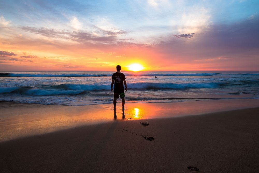 Man standing on the beach, sunset. Original public domain image from Wikimedia Commons