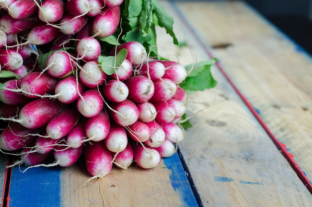 A large bunch of radishes on a wooden surface. Original public domain image from Wikimedia Commons