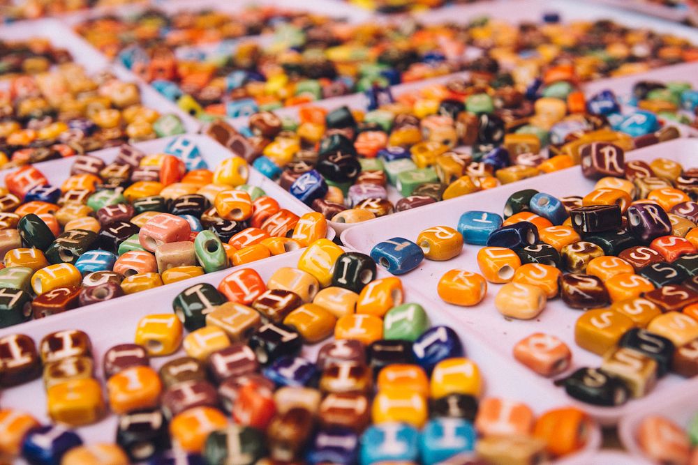 Trays of colorful beads with letters at a craft market. Original public domain image from Wikimedia Commons