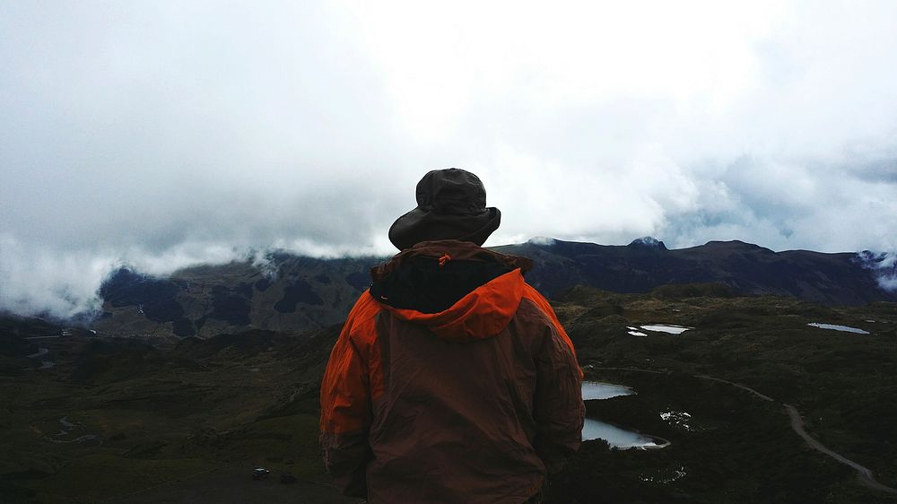 A person walking in a cloudy valley in Quito wearing a bright orange coat. Original public domain image from Wikimedia…
