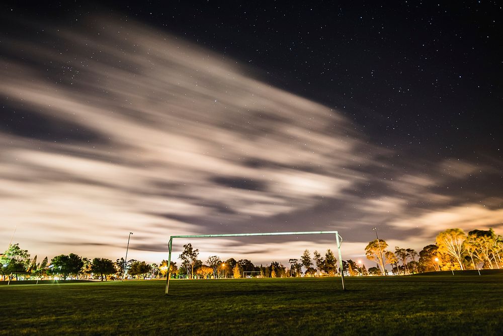 A soccer field at night with stars blurred in the sky. Original public domain image from Wikimedia Commons