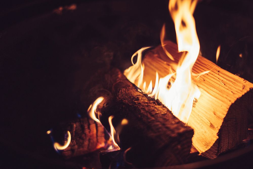 Logs of wood burn in an outdoor firepit. Original public domain image from Wikimedia Commons