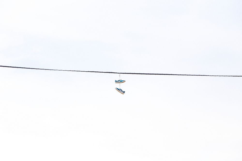 A pair of shoes hanging from a power line. Original public domain image from Wikimedia Commons