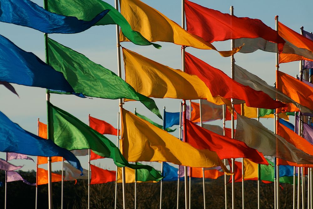 Rows of rainbow colored flags blow in the wind. Original public domain image from Wikimedia Commons