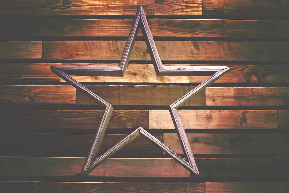 A wooden decoration in the shape of a hollow star against a wooden wall. Original public domain image from Wikimedia Commons