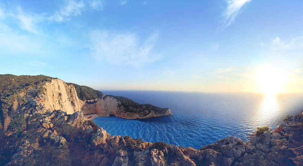 View of the sunrise in the coastal skyline from above the rocky cliffs of Navagio, Greece. Original public domain image from…