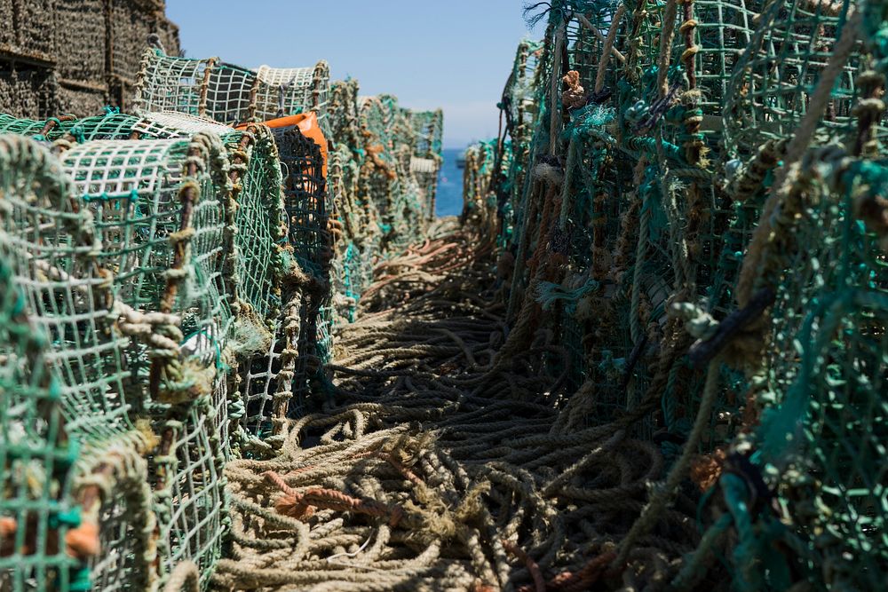 Crab and lobster traps stacked on top of one another with rope tied to them in Cascais. Original public domain image from…