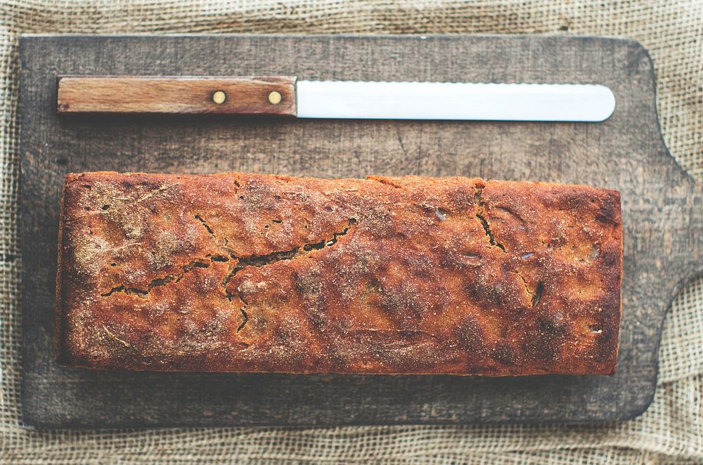 Freshly baked bread on a cutting board with a bread knife. Original public domain image from Wikimedia Commons