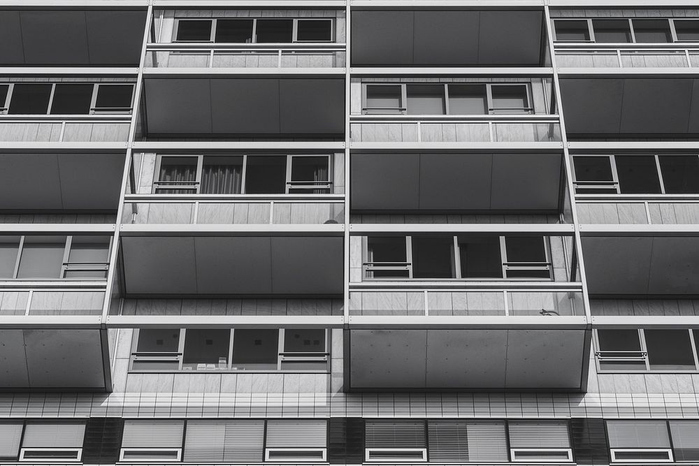 Black and white shot of urban building with balconies and windows. Original public domain image from Wikimedia Commons