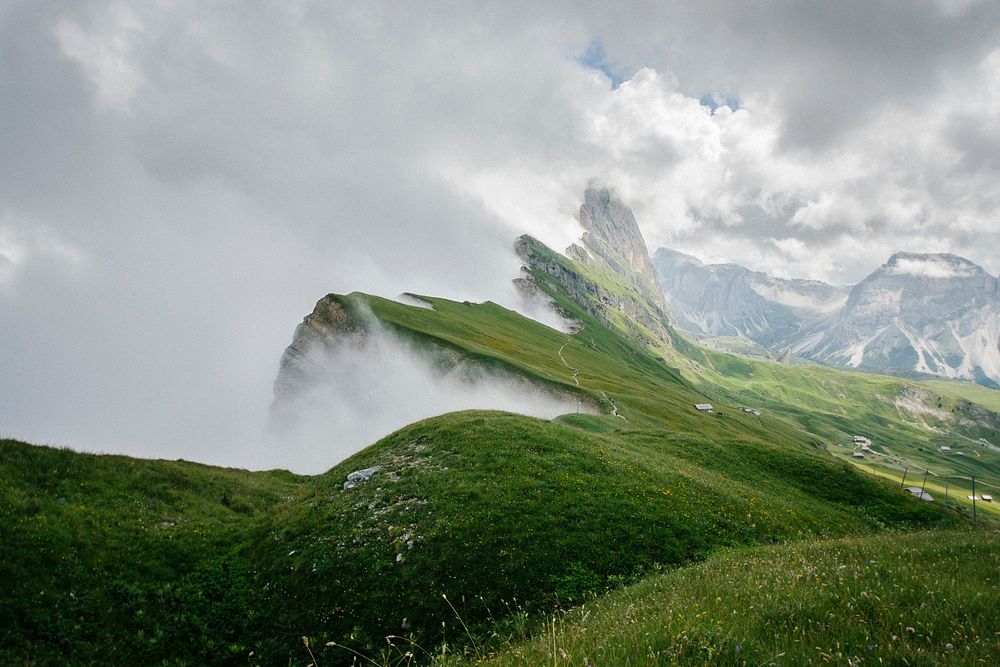 Grassy bluffs and snowy mountains of Seceda covered in clouds. Original public domain image from Wikimedia Commons
