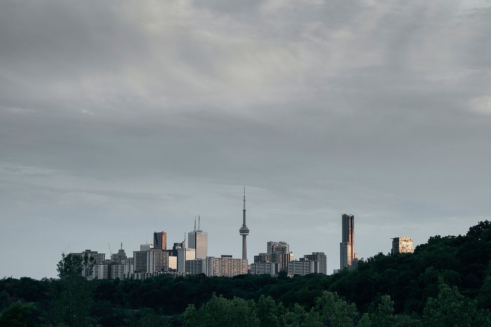 A city skyline with a tall broadcast tower under gray clouds. Original public domain image from Wikimedia Commons