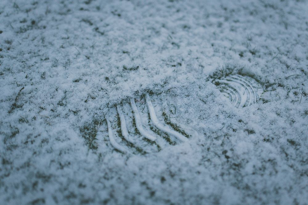 A footprint on a light layer of snow in the grass. Original public domain image from Wikimedia Commons