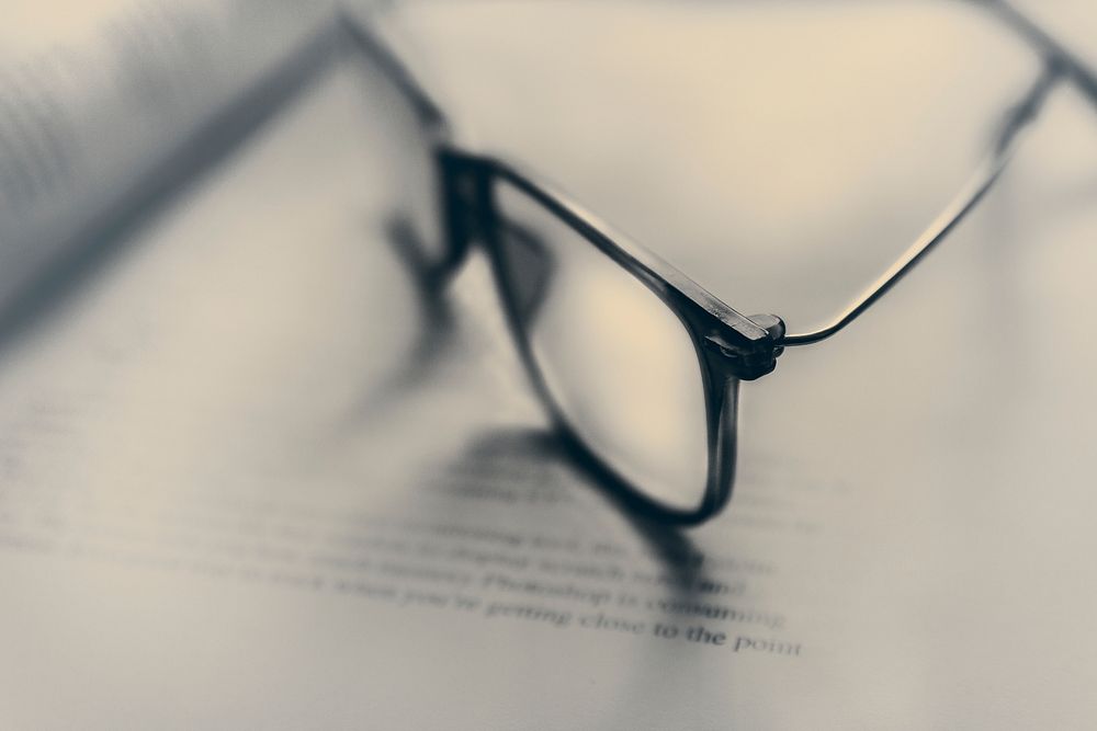 A pair of glasses on an open book. Original public domain image from Wikimedia Commons