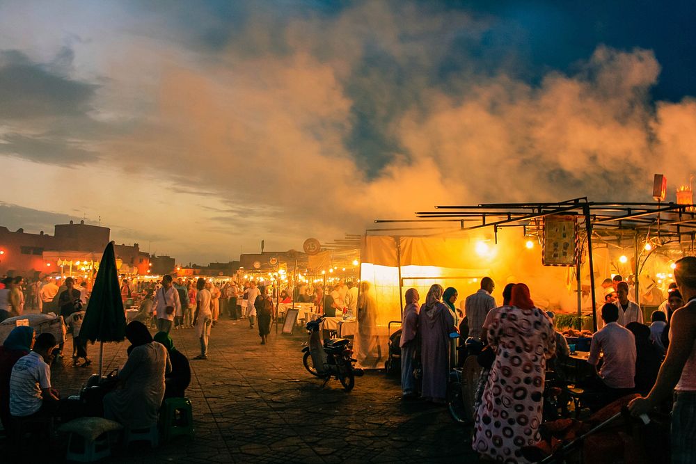 Orange glow and smoke rising up from a crowded bazaar on an evening. Original public domain image from Wikimedia Commons