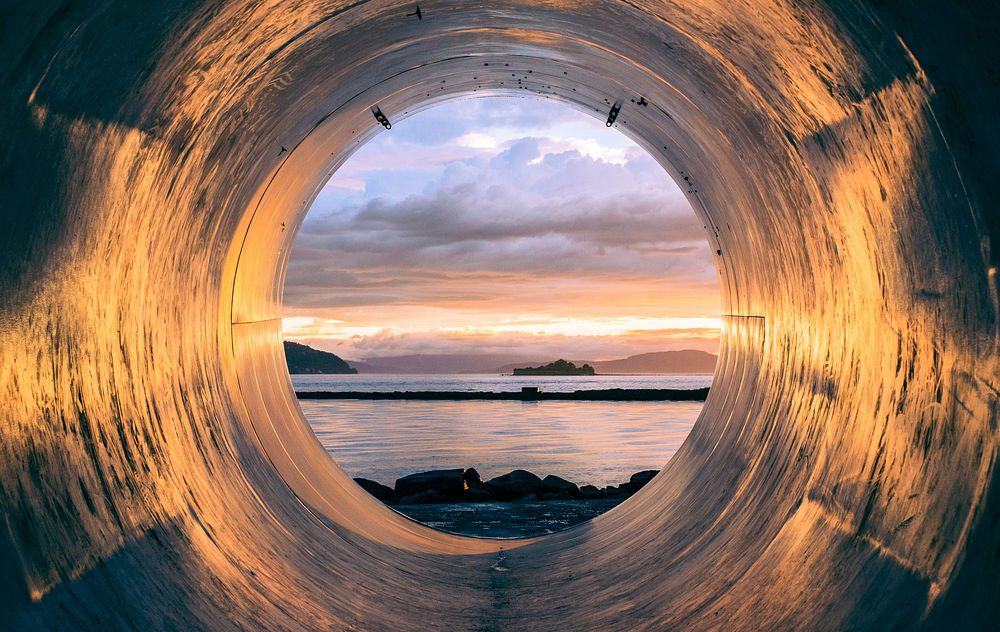 Sunset over the sea seen from the inside of a large pipe. Original public domain image from Wikimedia Commons