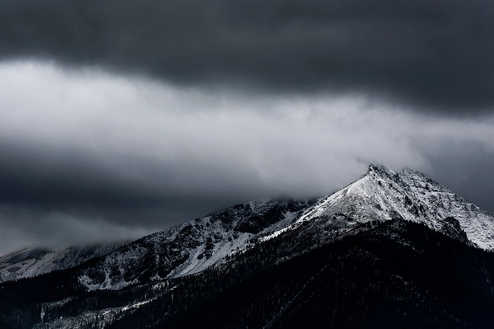 Sharp snow-capped mountain ridge in Silverthorne under heavy gray clouds. Original public domain image from Wikimedia Commons