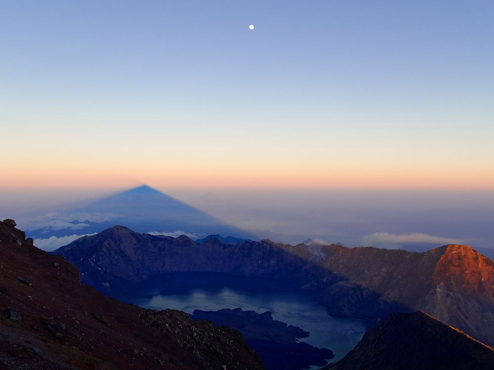 On high ground looking across a volcanic crater with the full moon in the distance. Original public domain image from…