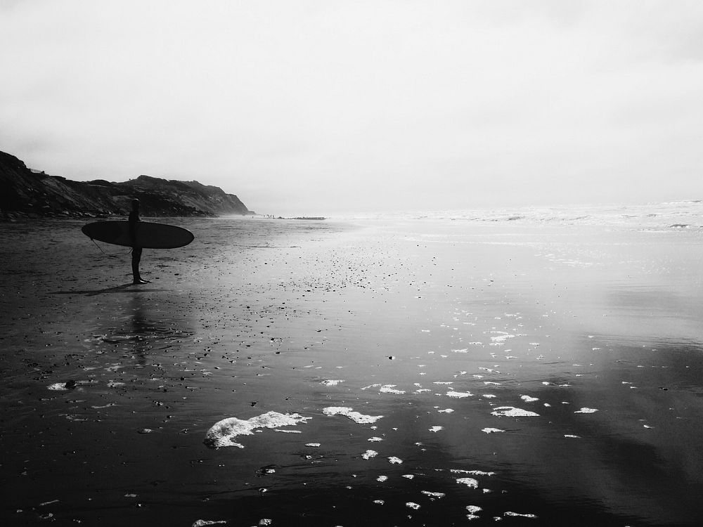 Surfer standing on the beach, gray scale. Original public domain image from Wikimedia Commons