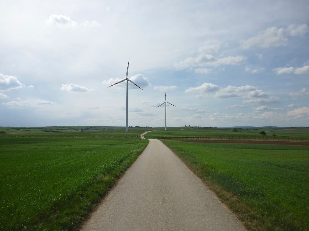A wind turbine / windmill in a field in Austria along with a cycle path. Original public domain image from Wikimedia Commons