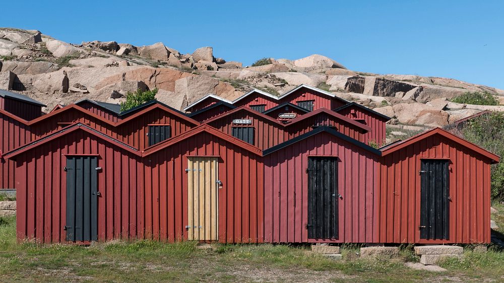 Red wooden beach huts among the glittering cliffs at Stångehuvud nature reserve in Lysekil, Sweden.
