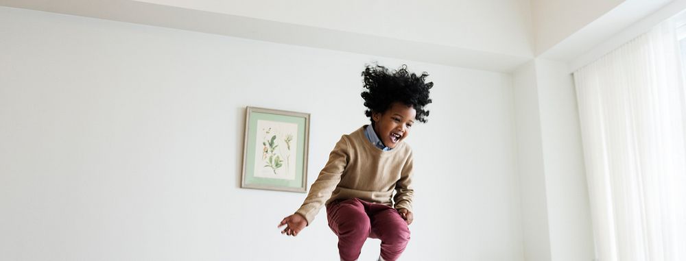 Young happy kid having fun jumping up and down on a bed social banner