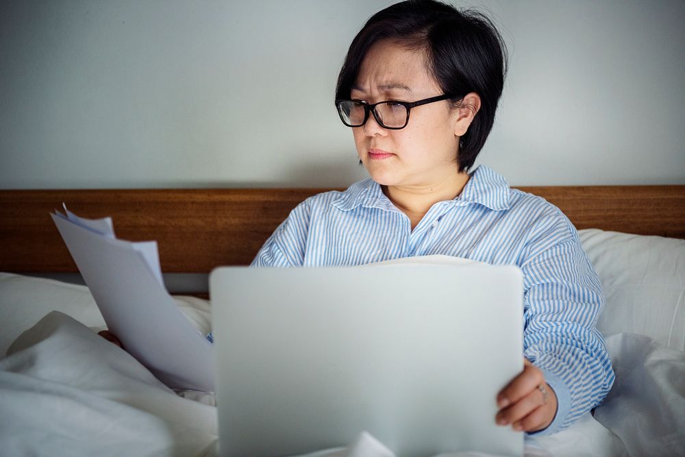 A woman working on a laptop in bed