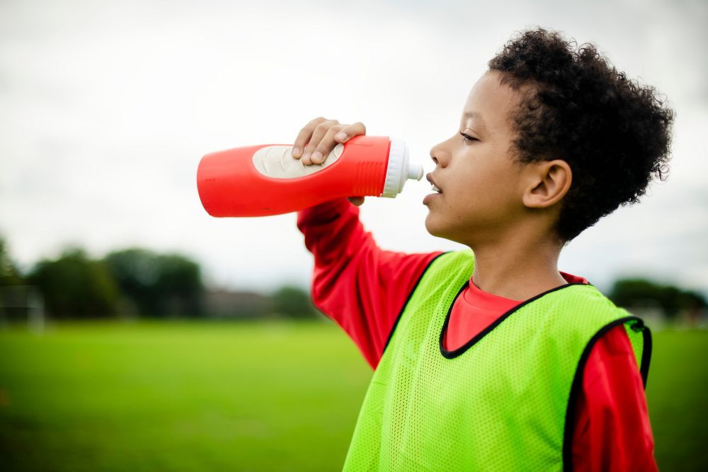 Thirsty junior football player drinking water