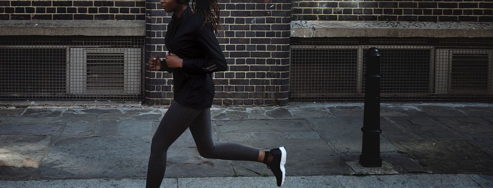 Woman listening to music while jogging in a city social banner