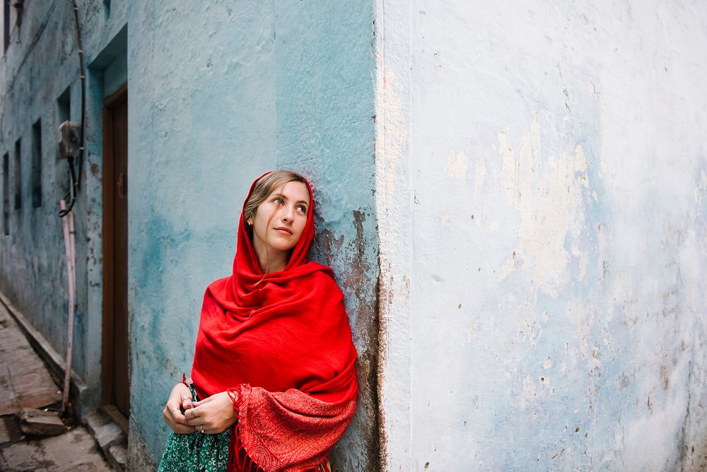 Western woman covered in a red scarf exploring Varanasi