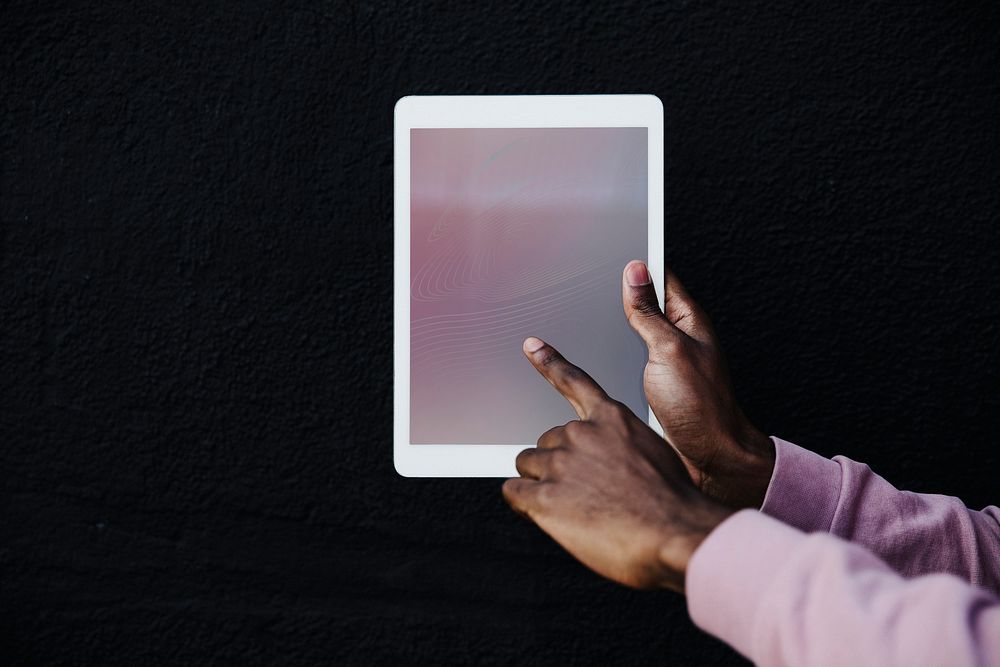 Hand holding a digital tablet on black background