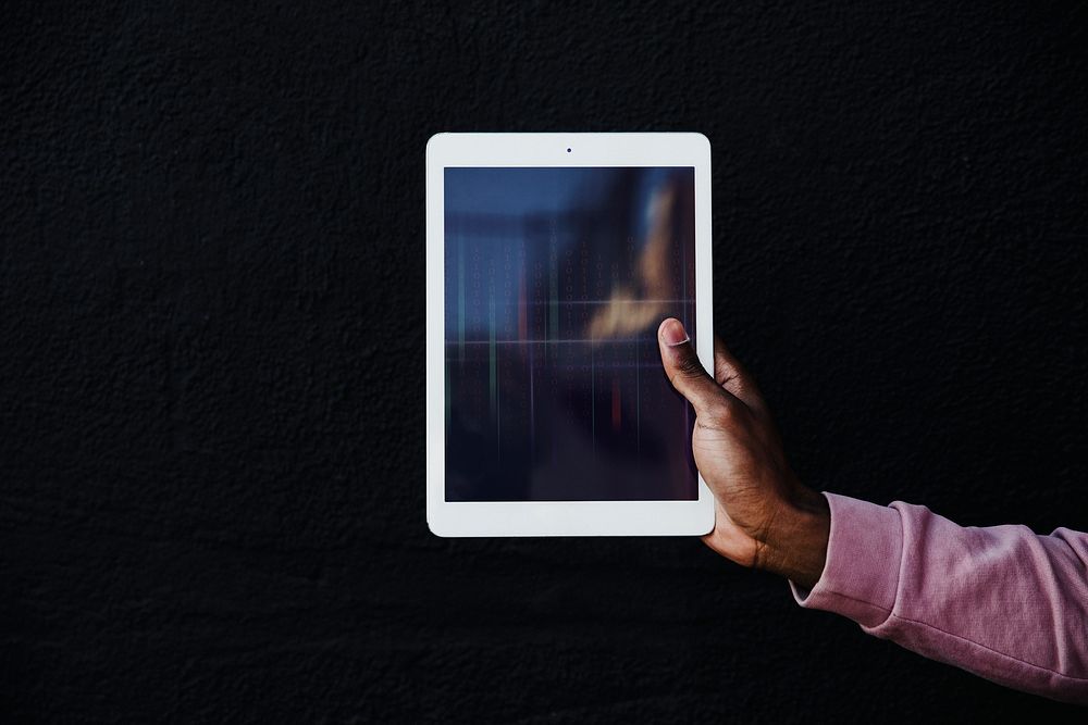 Hand holding a digital tablet on black background