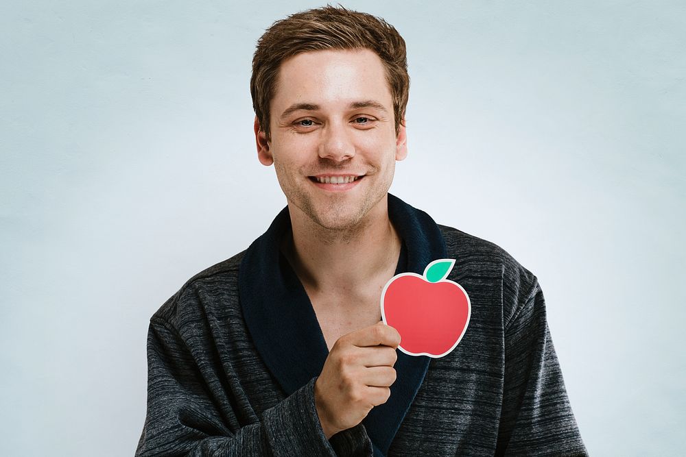Portrait of a handsome man in a dark rope showing a red apple symbol