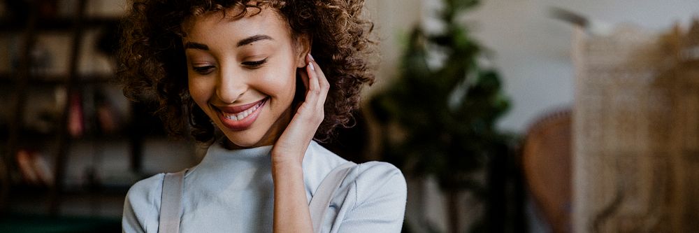 Cheerful black woman using her phone in living room