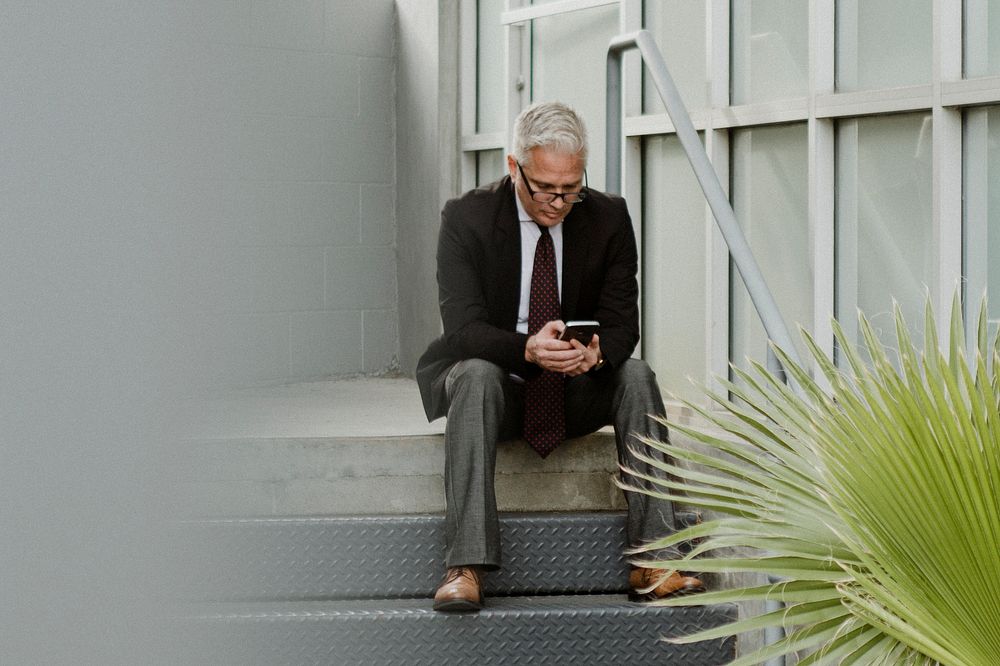 Entrepreneur sitting on the steps using his smartphone