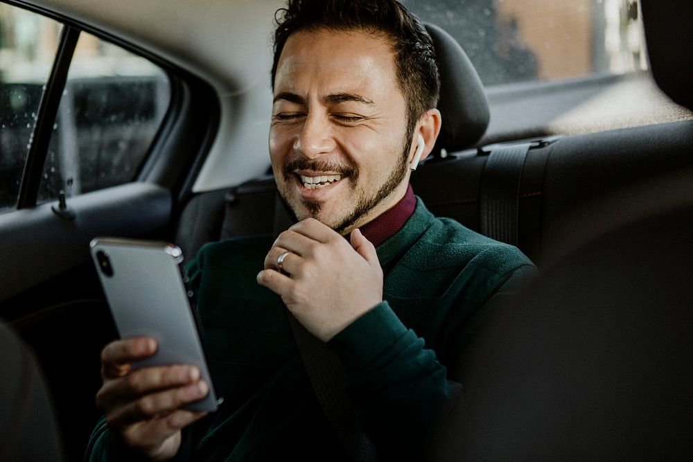 Happy man using his smartphone in the car
